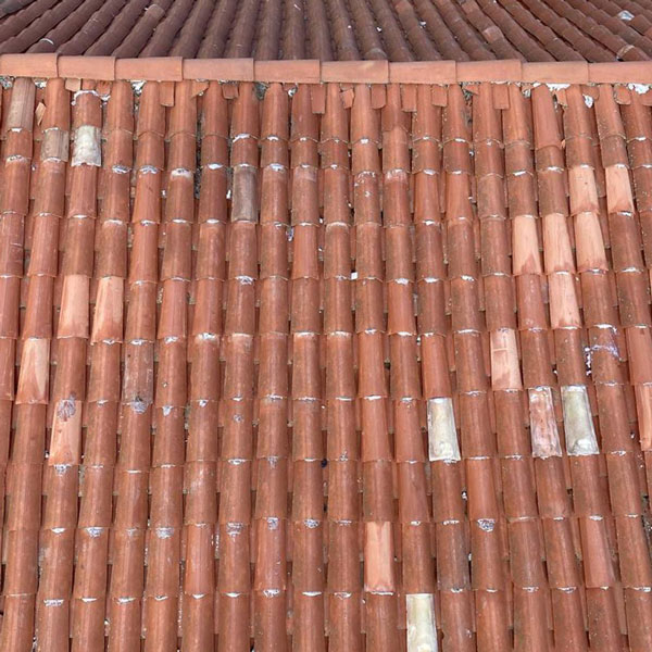 Tetto di tegole rosse in terracotta con alcune tegole scolorite, visto dall'alto.